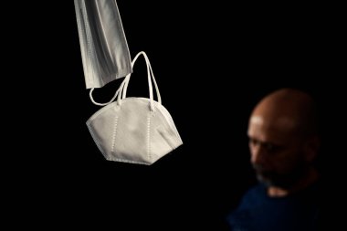 Siyah bir arka plan ve bir adama karşı iki koruyucu maskenin portresi. Salvador, Bahia, Brezilya.