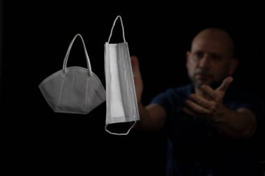 Siyah bir arka plan ve bir adama karşı iki koruyucu maskenin portresi. Salvador, Bahia, Brezilya.