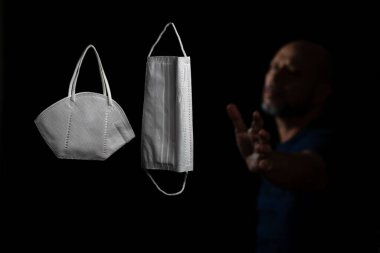 Siyah bir arka plan ve bir adama karşı iki koruyucu maskenin portresi. Salvador, Bahia, Brezilya.