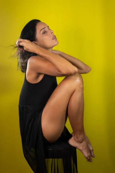 Portrét Modelu Sedí Dřevěné Lavičce Rukama Vlasech Proti Žlutému Pozadí — Stock fotografie