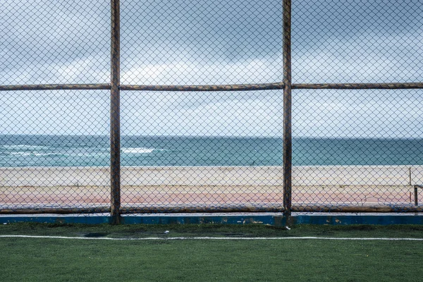 Sports fence seen during the rain against the ocean. Salvador, Bahia, Brazil.