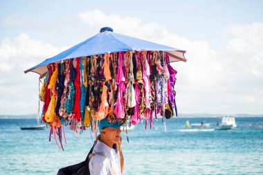 Salvador, Bahia, Brazil - June 04, 2022: Street vendors walk on the sand of Porto da Barra beach in Salvador, Bahia.