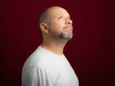 Kızıl arka plana bakan kel sakallı bir adamın portresi. Salvador, Bahia, Brezilya.