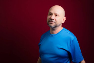 Kızıl arka planda kameraya bakan kel sakallı bir adamın portresi. Salvador, Bahia, Brezilya.