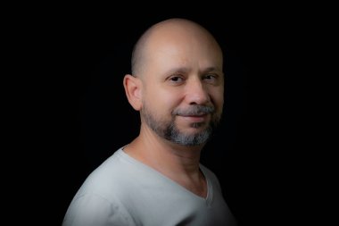 Siyah arka planda kameraya bakan kel sakallı bir adamın portresi. Salvador, Bahia, Brezilya.