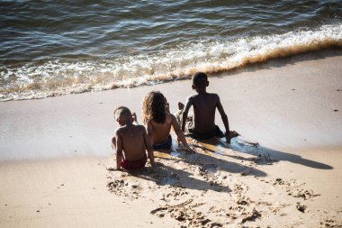Salvador, Bahia, Brazil - November 01, 2021: Three children play in the sand of Rio Vermelho beach in Salvador, Bahia in the late afternoon.