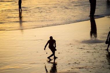 Salvador, Bahia, Brezilya - 01 Kasım 2021: Gençler Salvador, Bahia 'daki Rio Vermelho plajında gün batımına karşı frescoboll oynuyorlar.