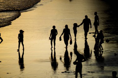 Salvador, Bahia, Brazil - November 01, 2021: People walking e se divertindo on the sand of Rio Vermelho beach in Salvador, Bahia, in the late afternoon.