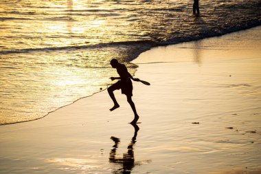 Salvador, Bahia, Brezilya - 01 Kasım 2021: Gençler Salvador, Bahia 'daki Rio Vermelho plajında gün batımına karşı frescoboll oynuyorlar.