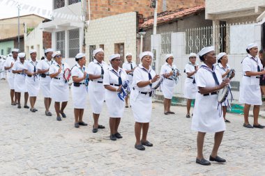 Men, women and children, members of the cultural group Chegana dos Marujos, dance and sing in costumes during a performance at the streets of Saubara, Bahia.