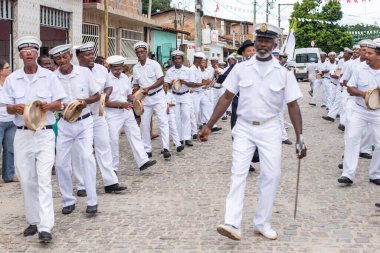 Men, members of the cultural group Chegana dos Marujos, dance and sing in costumes during a performance at the streets of Saubara, Bahia.
