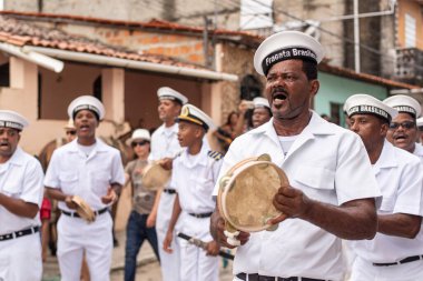 Men, members of the cultural group Chegana dos Marujos, dance and sing in costumes during a performance at the streets of Saubara, Bahia.