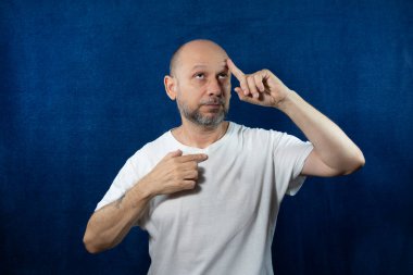 Portrait of a bearded bald man against blue background.