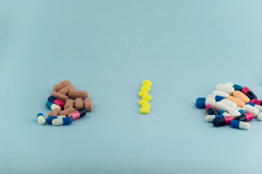Simple pile of colorful pills. Medicines, pills stacked on blue background. Medical supplies.