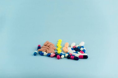 Simple pile of colorful pills. Medicines, pills stacked on blue background. Medical supplies.