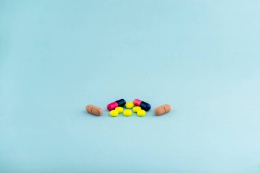 Simple pile of colorful pills. Medicines, pills stacked on blue background. Medical supplies.