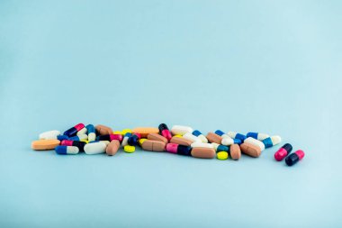 Simple pile of colorful pills. Medicines, pills stacked on blue background. Medical supplies.