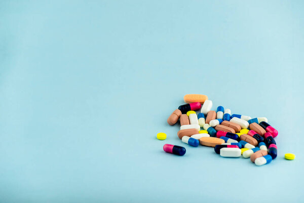 Simple pile of colorful pills. Medicines, pills stacked on blue background. Medical supplies.