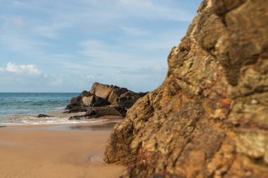 A wave breaks about a rock during a curtain on the sea. Farol da Barra beach, Salvador, Brazil.