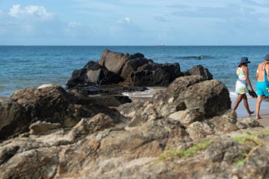 A wave breaks about a rock during a curtain on the sea. Farol da Barra beach, Salvador, Brazil.