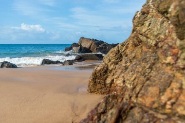 A wave breaks about a rock during a curtain on the sea. Farol da Barra beach, Salvador, Brazil.