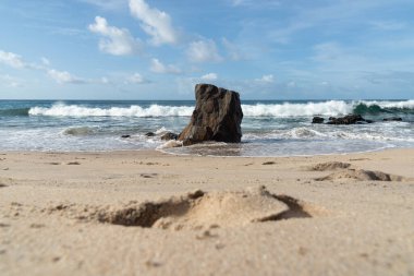 A wave breaks about a rock during a curtain on the sea. Farol da Barra beach, Salvador, Brazil.