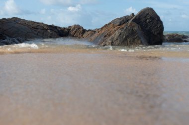 A wave breaks about a rock during a curtain on the sea. Farol da Barra beach, Salvador, Brazil.