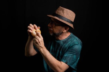 Siyah arka planda mandalina soyan gözlüklü ve sakallı bir adam. Salvador, Bahia, Brezilya.