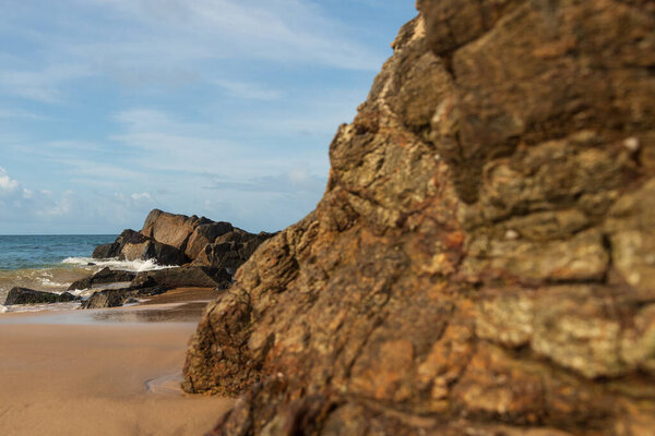 A wave breaks about a rock during a curtain on the sea. Farol da Barra beach, Salvador, Brazil.