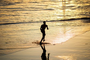 Salvador, Bahia, Brezilya - 01 Kasım 2021: Gençler Salvador, Bahia 'daki Rio Vermelho plajında gün batımına karşı frescoboll oynuyorlar.