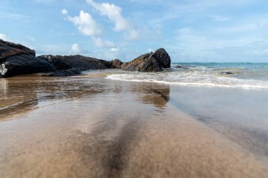 A wave breaks about a rock during a curtain on the sea. Farol da Barra beach, Salvador, Brazil.