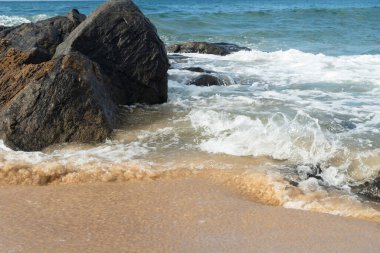 A wave breaks about a rock during a curtain on the sea. Farol da Barra beach, Salvador, Brazil.