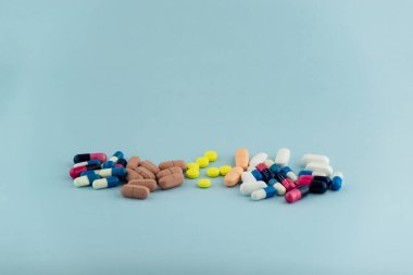 Simple pile of colorful pills. Medicines, pills stacked on blue background. Medical supplies.