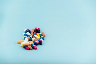 Simple pile of colorful pills. Medicines, pills stacked on blue background. Medical supplies.