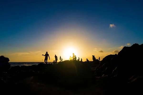 Silhouette of people on top of the beach rocks. Late afternoon in Salvador, Bahia, Brazil.
