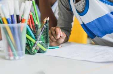 Salvador, Bahia, Brazil - December 16, 2014: Detail of student hands painting writing with colored pencils. Salvador, Bahia, Brazil.