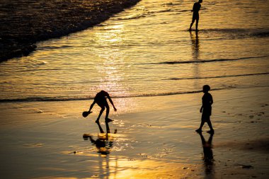 Salvador, Bahia, Brazil - November 01, 2021: Young people playing frescoboll against sunset at Rio Vermelho beach in Salvador, Bahia.