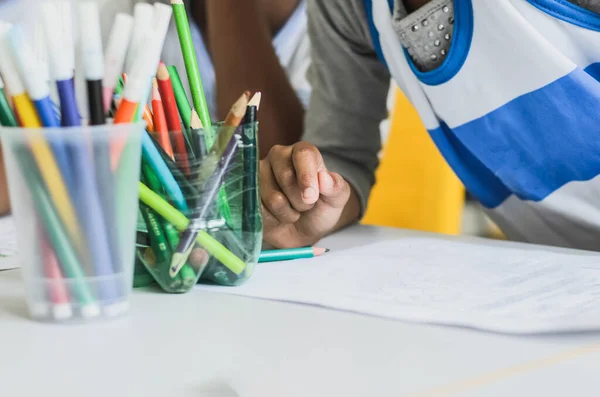 Salvador, Bahia, Brazil - December 16, 2014: Detail of student hands painting writing with colored pencils. Salvador, Bahia, Brazil.