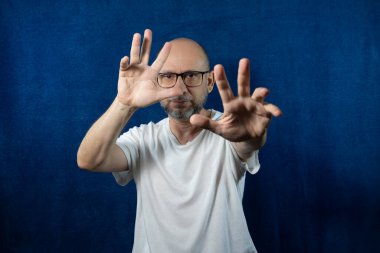 Portrait of a bearded bald man against blue background.
