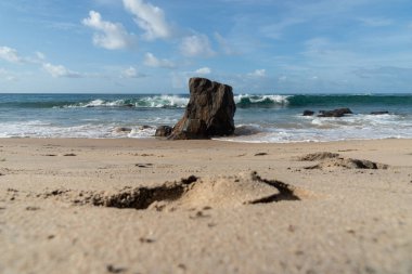 A wave breaks about a rock during a curtain on the sea. Farol da Barra beach, Salvador, Brazil.