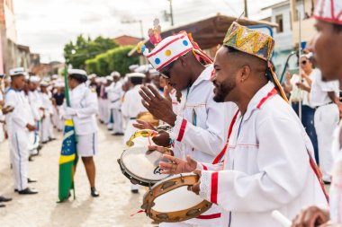 Saubara, Bahia, Brazil - August 06, 2022: Cultural demonstration called Encontro de Chegancas in Saubara, Bahia. Members of a Marujada wear white clothes with colors and play percussion musical instruments.