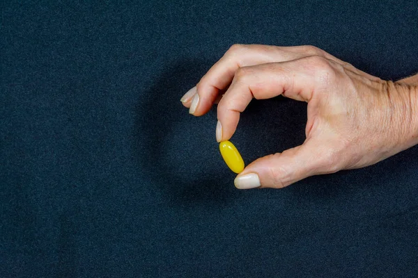 Yellow Pill Held Fingers One Hand Black Background Medical Material — Stockfoto