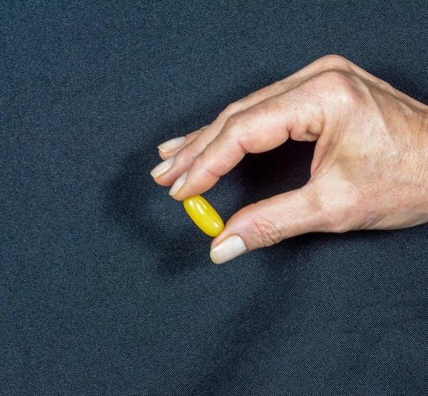 Желтая Таблетка Удерживаемая Пальцами Одной Руки Черном Фоне Медицинский Материал — стоковое фото