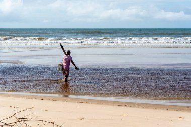 Fisherman is seen walking on the beach. Guaibim beach in the city of Valenca, Bahia, Brazil.