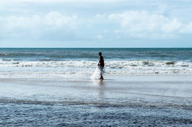 Fisherman manipulating the fishing net on the beach. Guaibim beach in the city of Valenca, Bahia, Brazil.