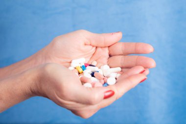 Several pills in a persons palm against blue background. Medical supplies.      