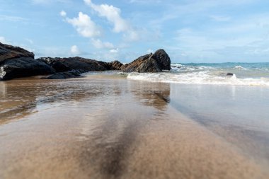 A wave breaks about a rock during a curtain on the sea. Farol da Barra beach, Salvador, Brazil.