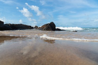 A wave breaks about a rock during a curtain on the sea. Farol da Barra beach, Salvador, Brazil.