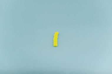Simple pile of yellow pills. Medicines, pills stacked on blue background. Medical supplies.