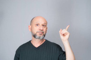 Portrait of mature man standing on white background. Bald bearded man making gestures. Formal style.